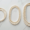 Bahraini pearl necklaces in different lengths including choker and princess styles displayed on a white stand