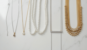 A flat lay of necklaces ranging from simple silver chains to diamond and pearl luxury pieces on white background