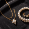 High-karat Bahraini gold jewelry set with pearls displayed as investment pieces on dark velvet