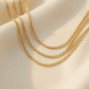 Three layered delicate gold necklaces at different lengths styled on a woman's collarbone
