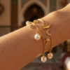 Gold charm bracelet with Bahraini motifs including a pearl, date palm and dhow charm on a wrist