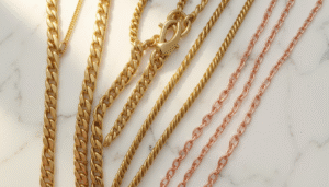 Gold chain necklaces in Bahrain displayed on a white marble surface showing curb, rope, and Figaro chain styles