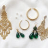 Variety of gold earring styles for Bahraini women displayed on white velvet