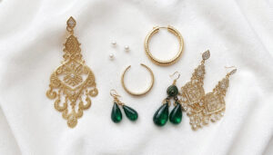 Variety of gold earring styles for Bahraini women displayed on white velvet