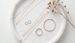 A curated capsule jewelry collection laid out on a white marble tray including gold earrings, necklace, ring, and bracelet