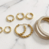 Elegant gold hoop earrings in Bahrain displayed on white marble surface with soft warm lighting