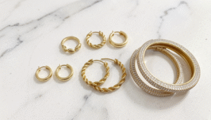 Elegant gold hoop earrings in Bahrain displayed on white marble surface with soft warm lighting