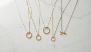 Minimalist gold necklace styles displayed on a white marble surface, featuring delicate chains and small pendants